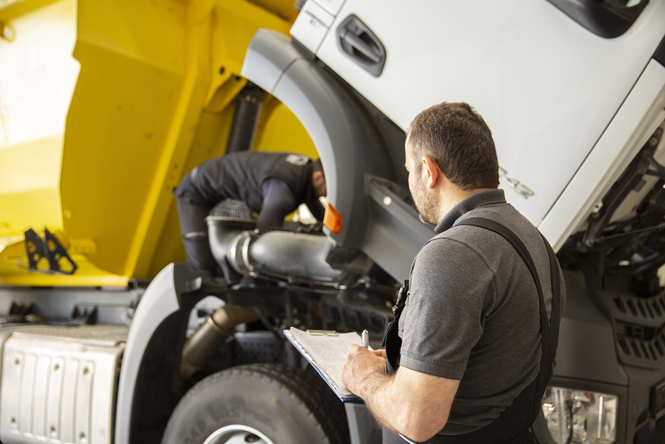 picture is of a person with a tablet standing next to a heavy vehicle