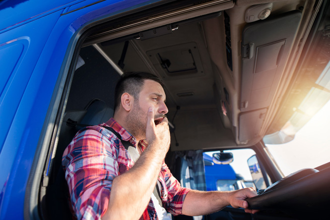 Image is of a man giving the thumbs up while wearing his seatbelt in the cab of his truck. 