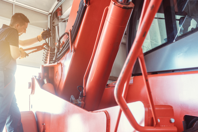 Image is of a man working on a agricultural implement